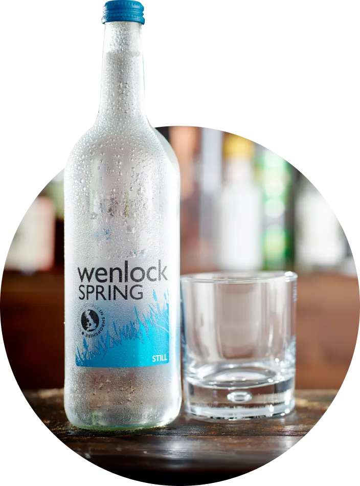 a bottle of wenlock spring next to a glass